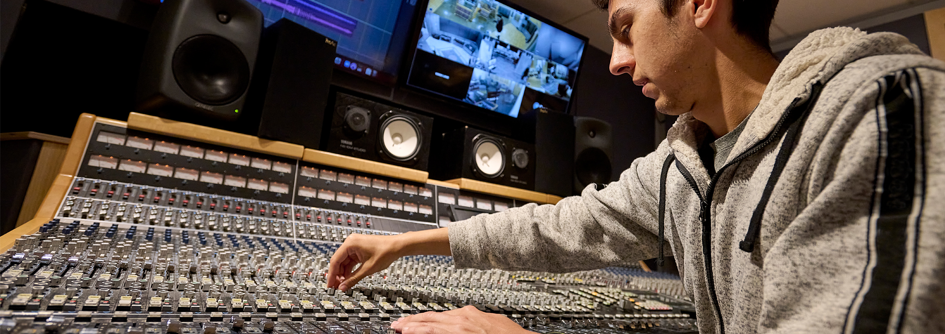 A student uses an audio mixer in the New England School of Communications audio suite