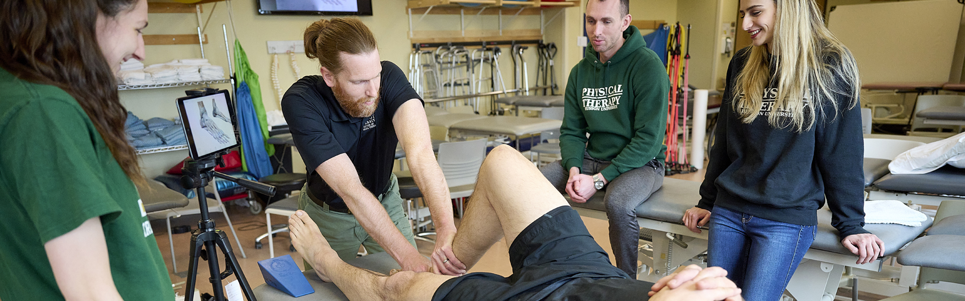 A faculty member works with students in a physical therapy lab