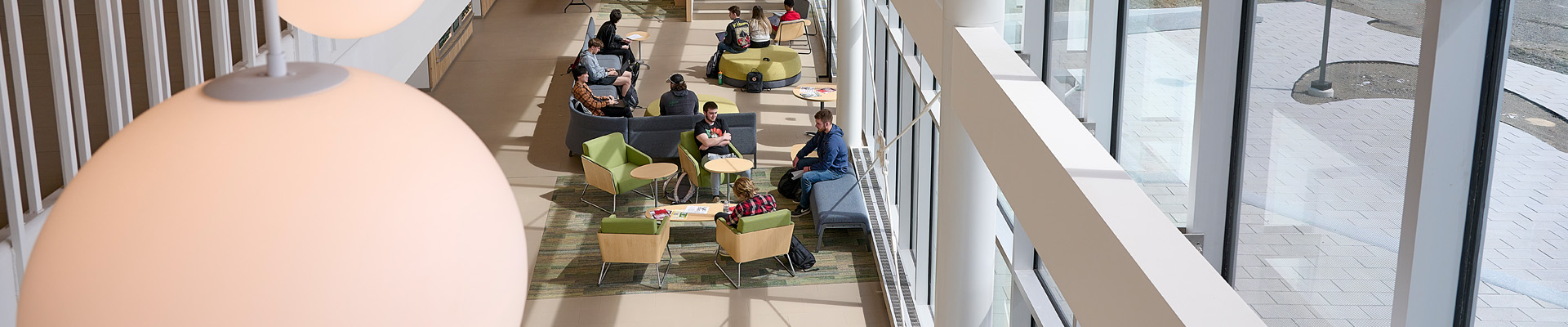 Interior view of Harold Alfond Hall where students are seated, talking and studying