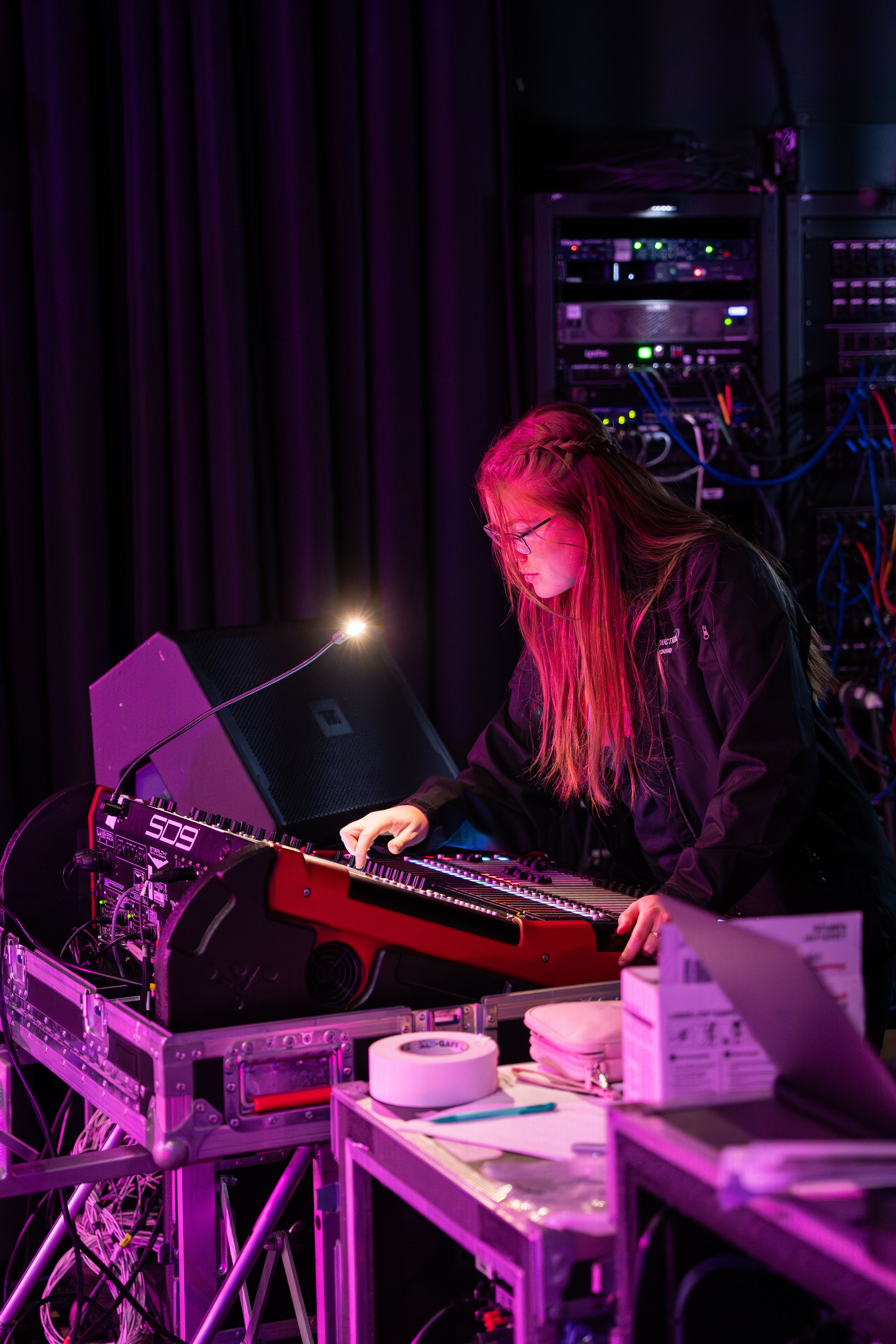 A New England School of Communications graduate works at a concert as a live sounds technician