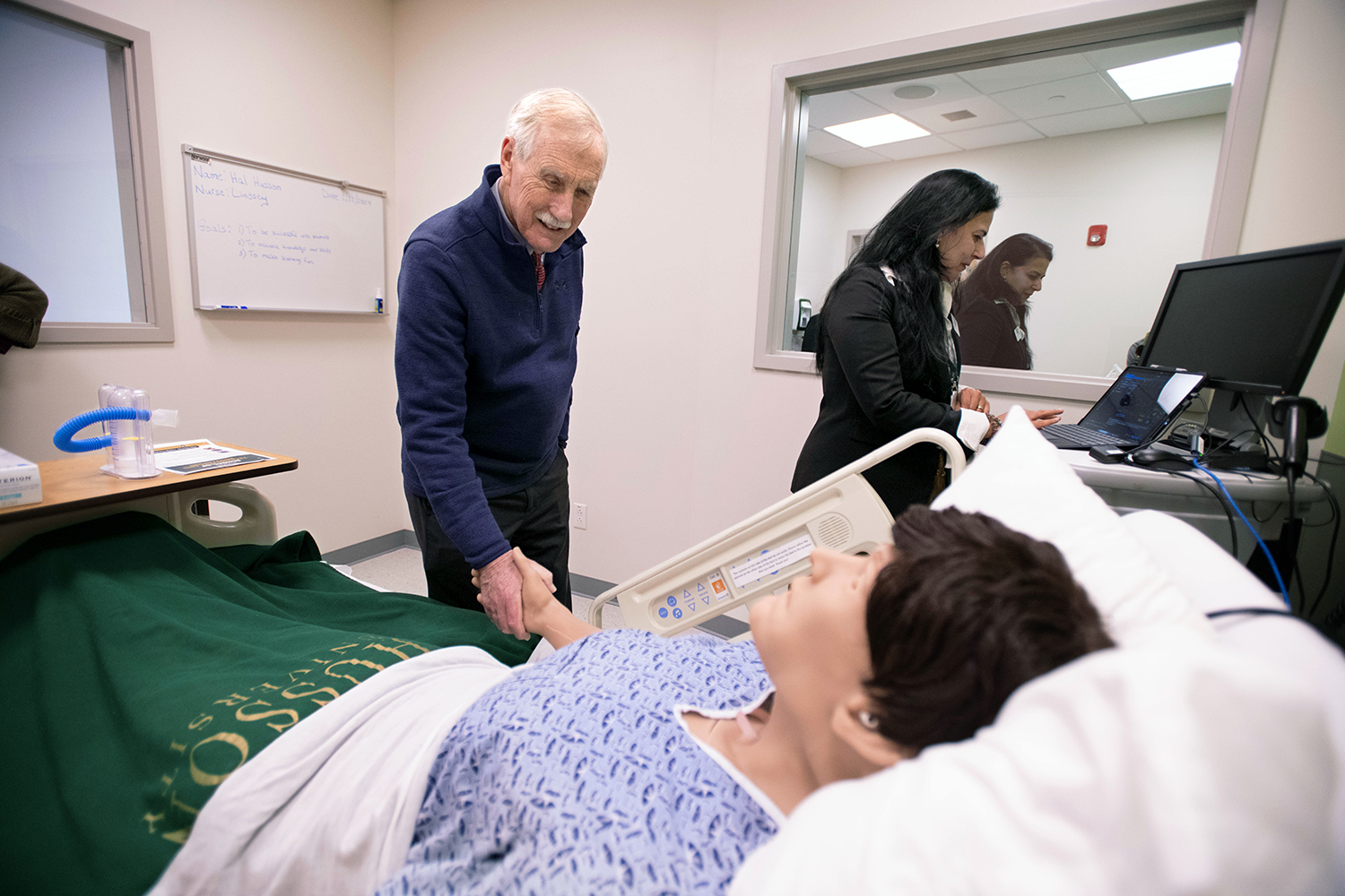 Senator Angus King is shown in a Husson University simulation lab shaking the hand of an AI Manikin. 