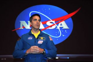Christopher Cassidy speaking in front of NASA logo