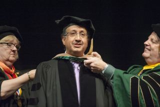 A man and two woman preparing for commencement ceremony