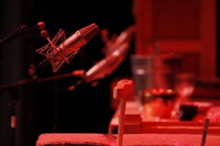microphones on stands lined up under red lighting