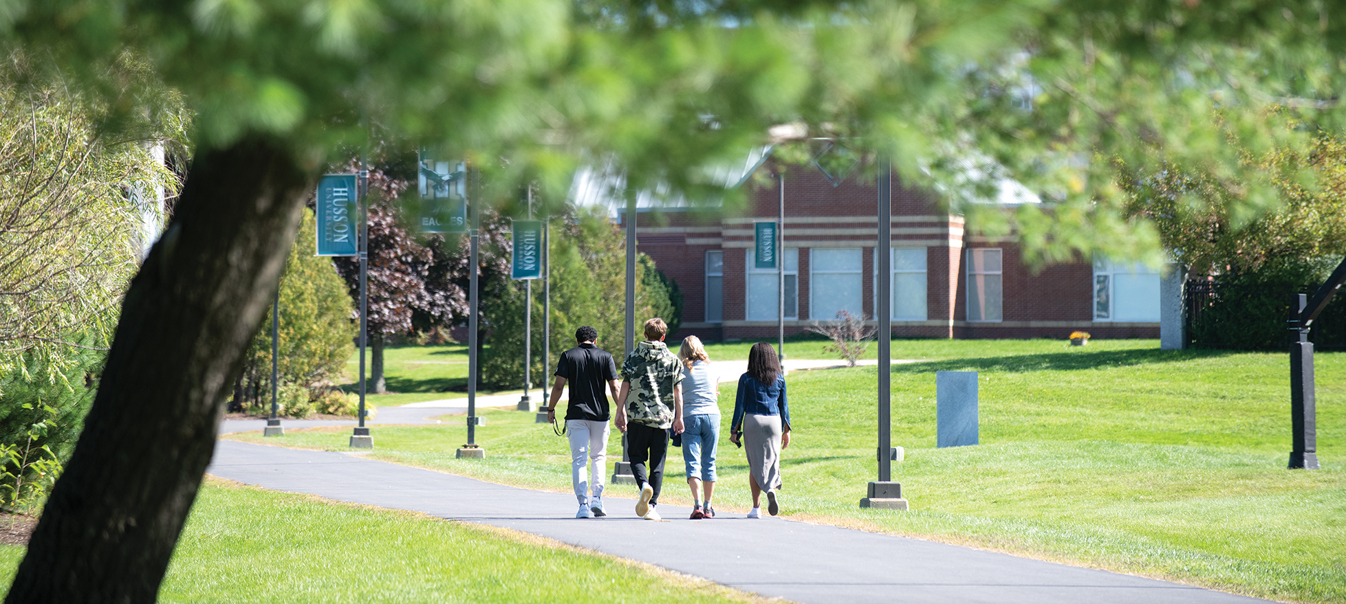 students walking along a pathway on the campus of Husson University
