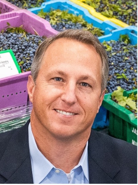 Headshot of Tony Shurman with crates of blueberries in the background