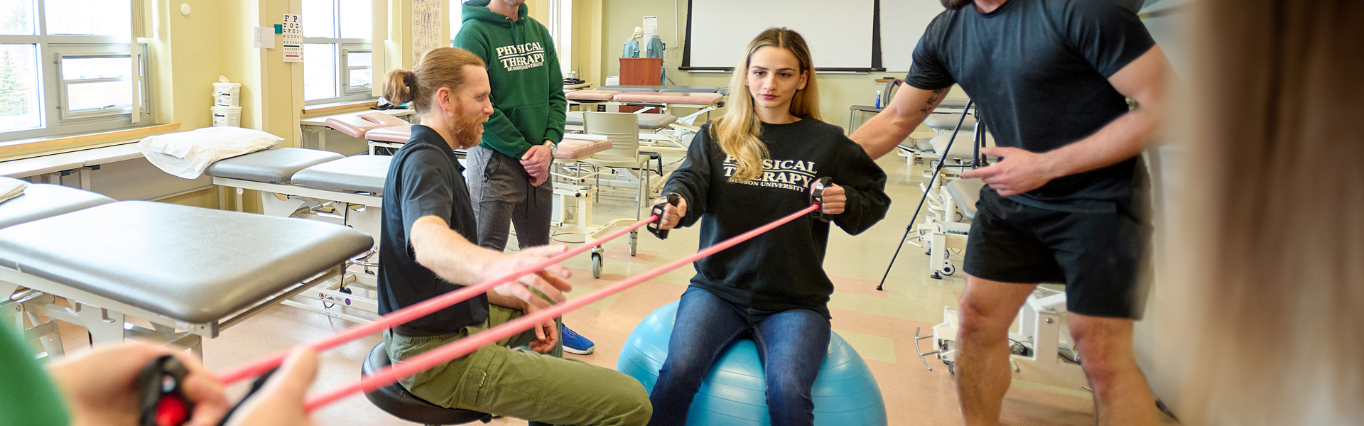 A faculty member works with students in a physical therapy lab