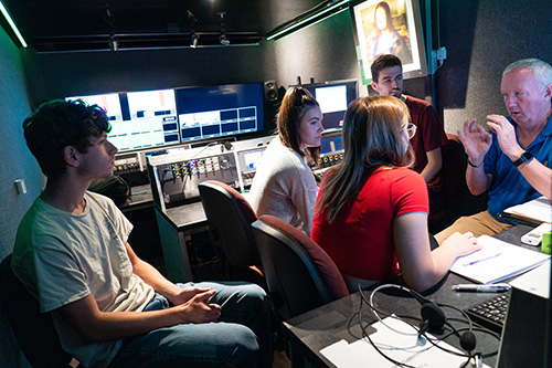 Four students listen to a faculty member in the remote production trailer