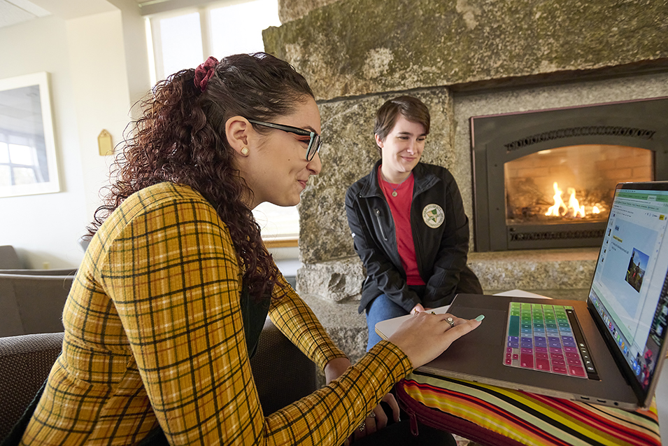 Students study in the campus center in front of a fireplace
