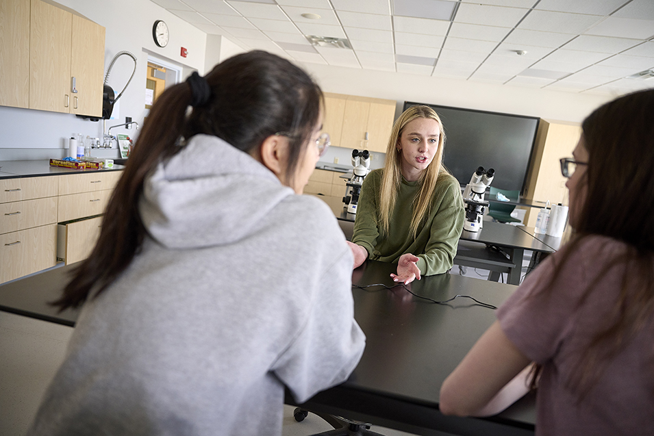 Students interact in a lab that uses microscopes