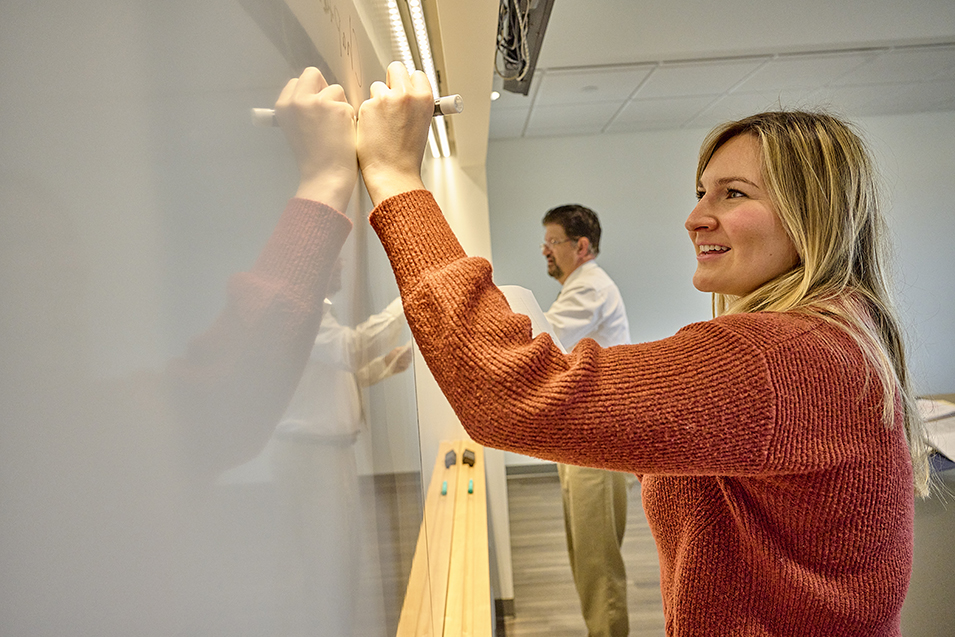 A student writes on a white board in a classroom in Harold Alfond Hall