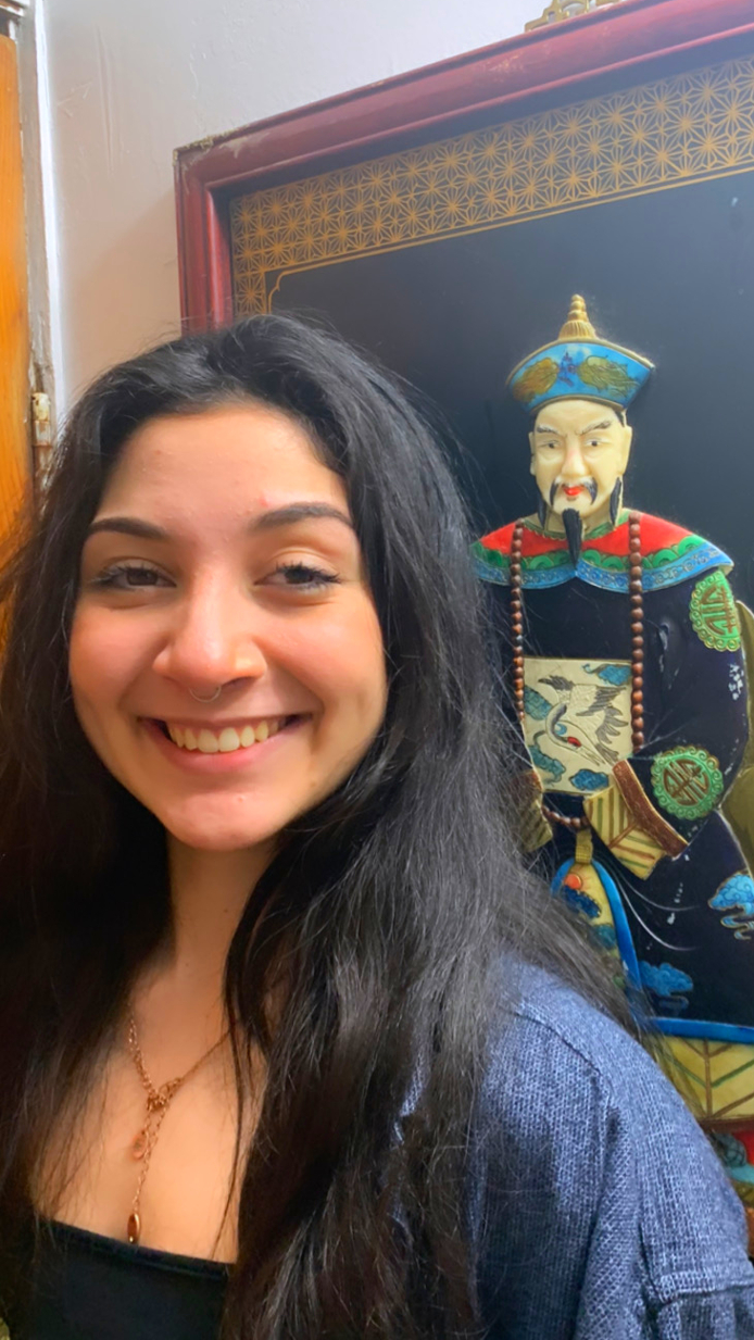 Louisa Colucci in front of a painting of a man in traditional ancient Chinese clothes