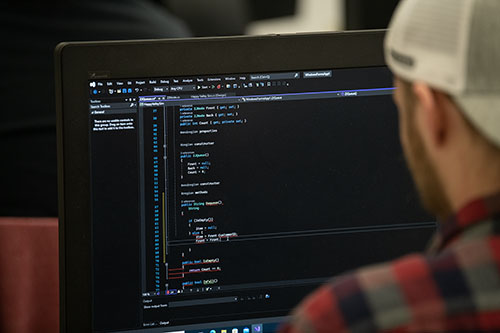 A student writes code on a computer for a software development class