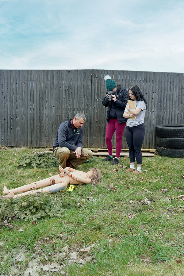 Students and faculty work in the field with a mock crime scene