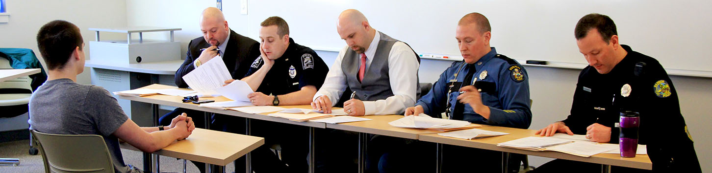 A criminal justice student sits in front of a mock oral board.