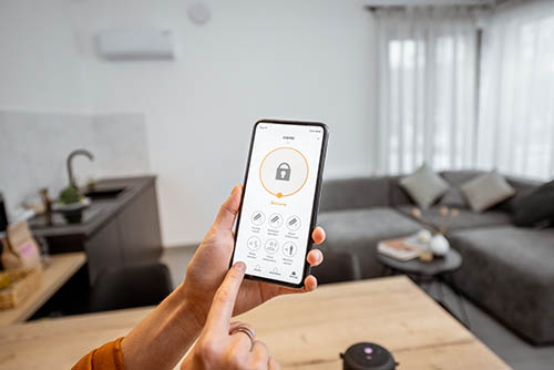 A hand is holding a smartphone that has an app open to secure a house