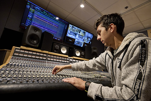 A student works in an audio engineering studio mixing sound