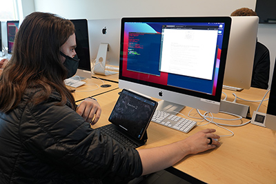 student works on developing software in front of a computer