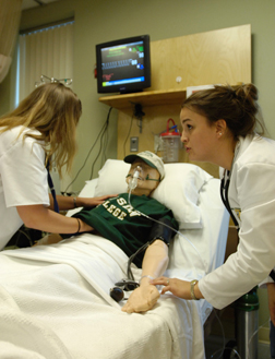 Two nursing students work with a simulation mannequin