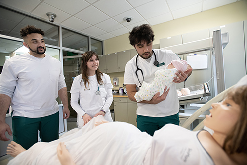 three students work in a nursing sim with a sim manikin lab 