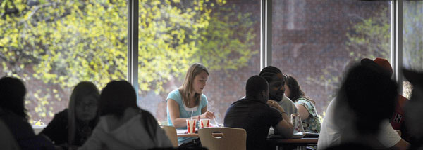 A student eating lunch and studying in the campus center.