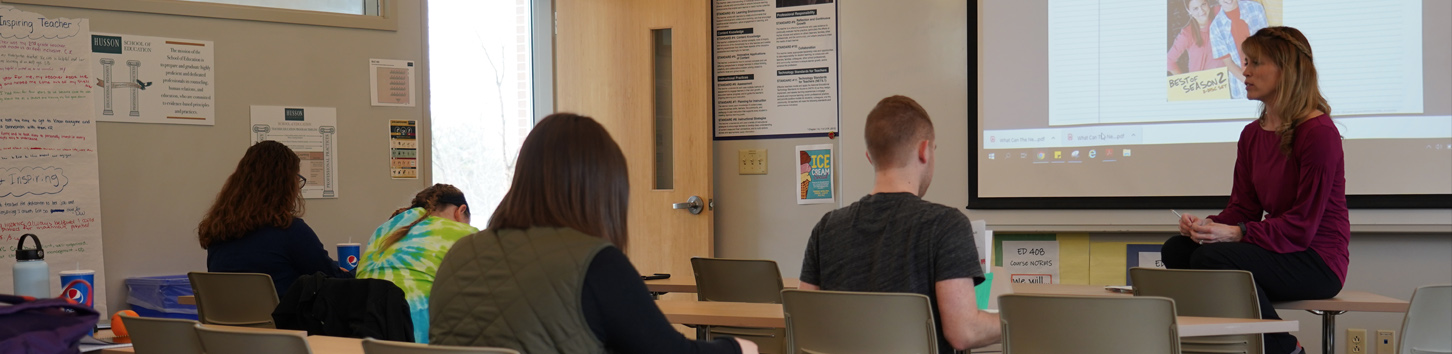 Students listen to faculty in a school of education class