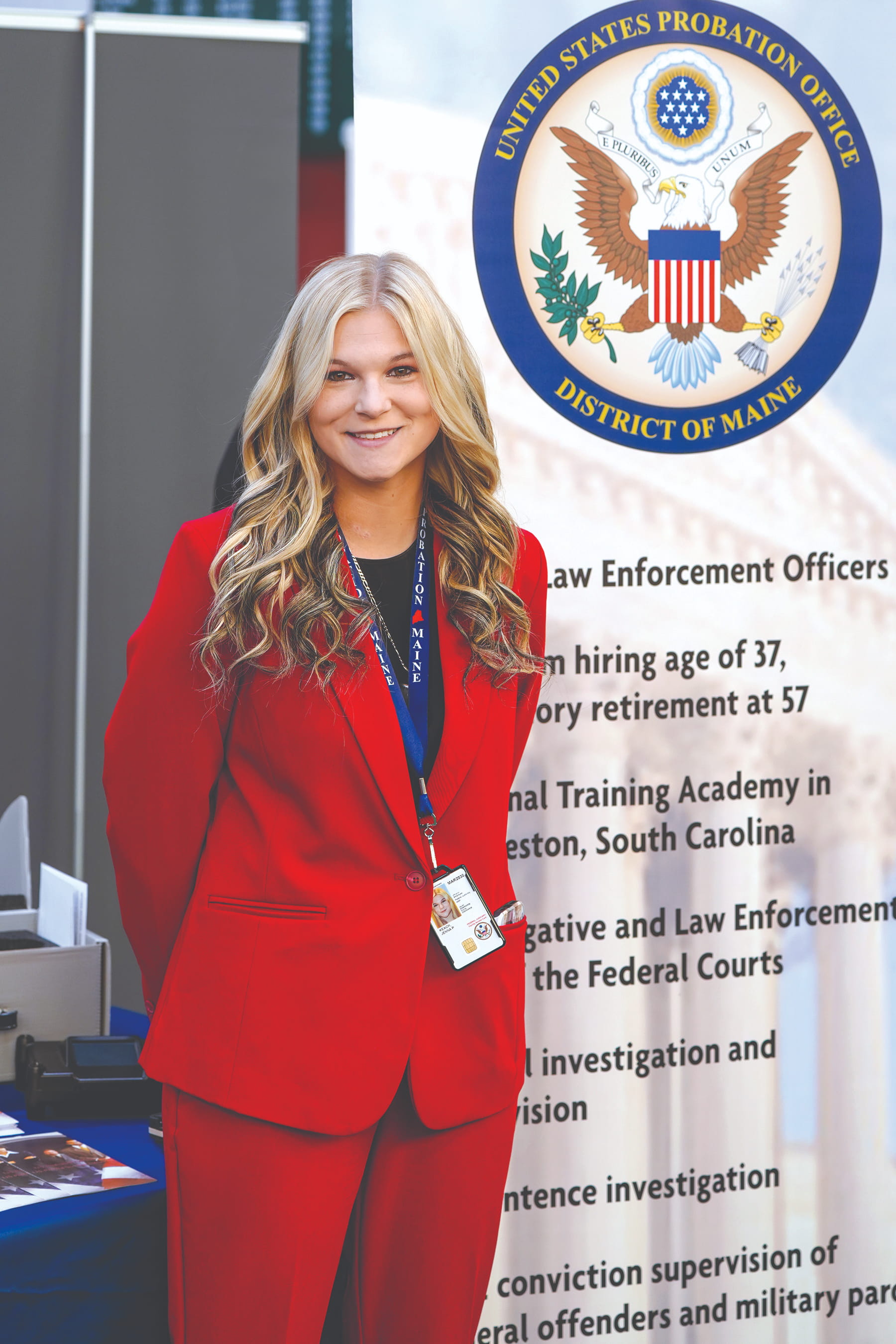 Jenna Keach, a Husson grad, standing in front of a United States Probation Office District of Maine informational banner. 