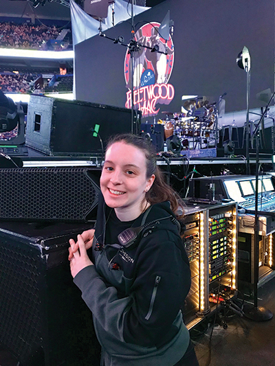 Husson University grad standing in front of audio equipment at a concert