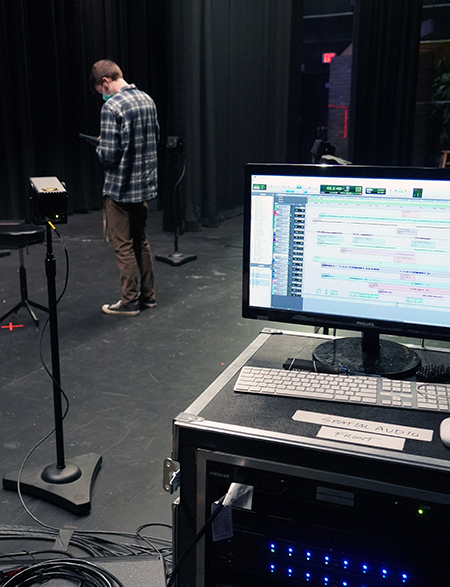 An audio engineering student works with spatial audio equipment in the Gracie Theatre