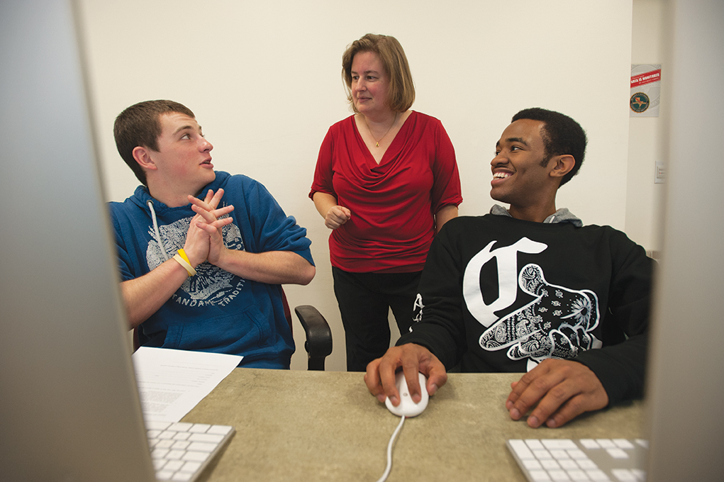 Instructor Laura Gurney talking with two of the students in a previous Hour-of-Code class.