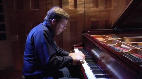 Michael Hawley sits at a piano during a performance