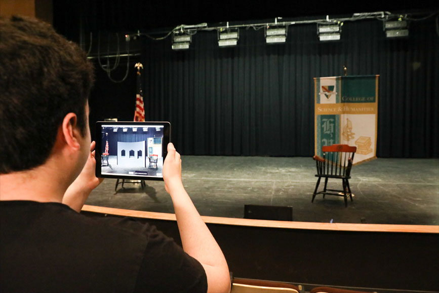 A student uses the augmented reality ipad app on stage of a local theater 