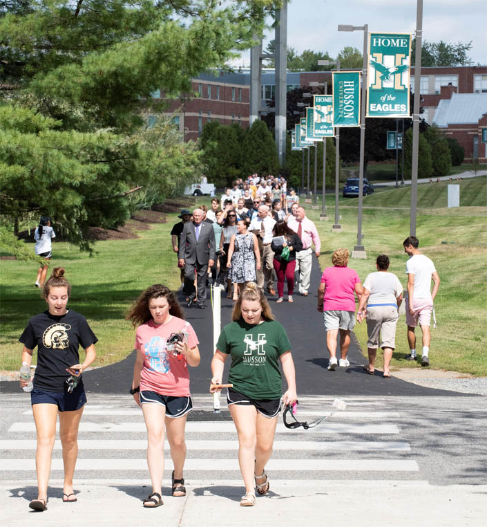 Students walk to convocation on the campus of Husson University