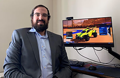 Husson University esports coordinator Joel Madru sitting in front of a computer