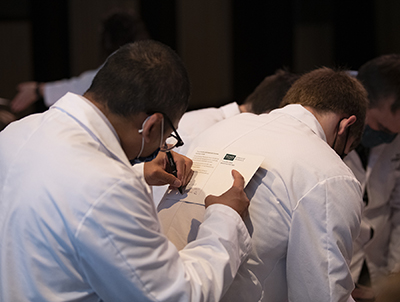 Pharmacy student uses another student's back as a surface on which to write a thank-you note