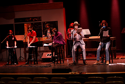 Students standing in front of microphones on a stage.