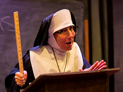 Nun holding a ruler while standing at a podium