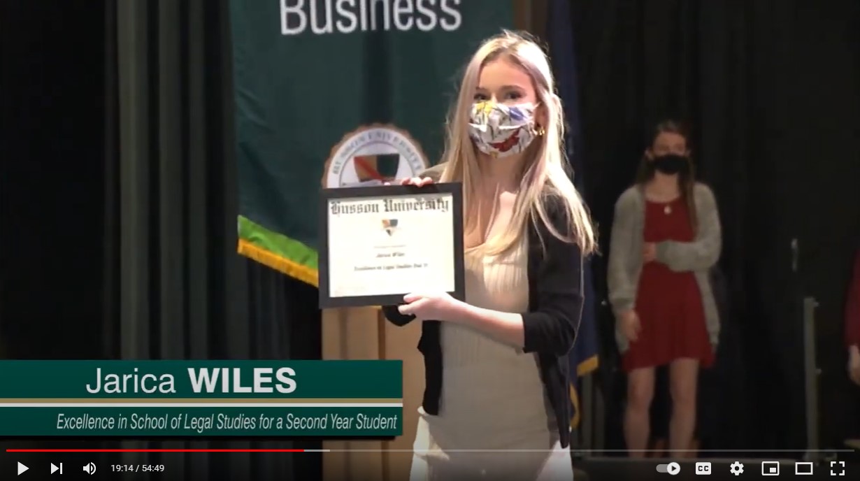 girl posing with award in front of College of Business banner