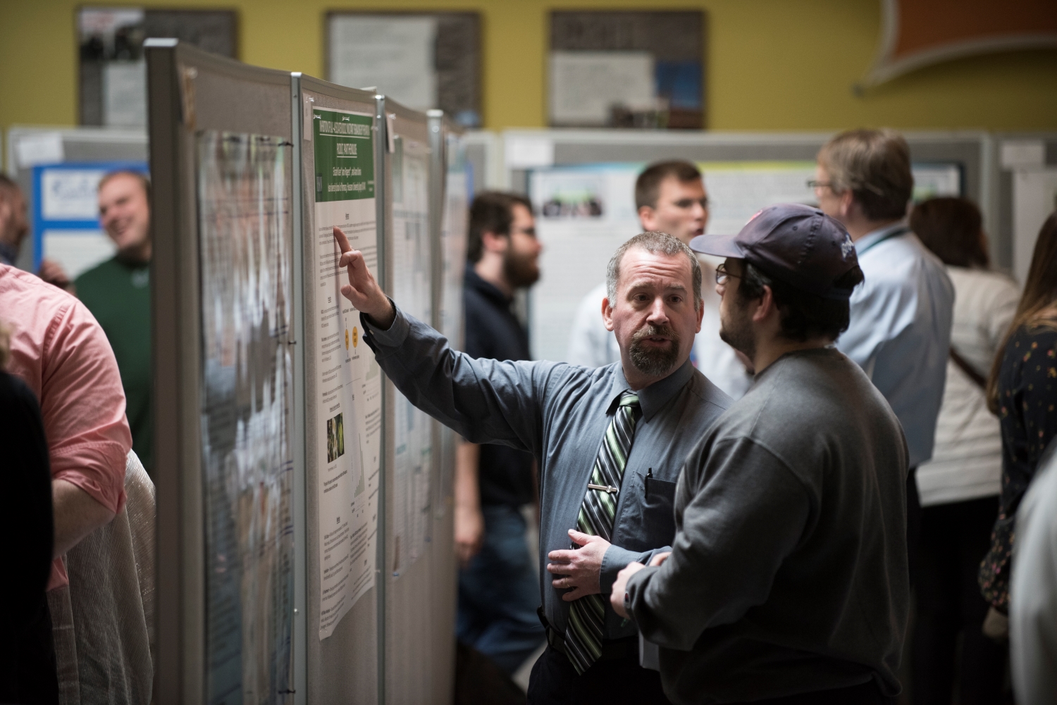 man explains information on a poster to another man