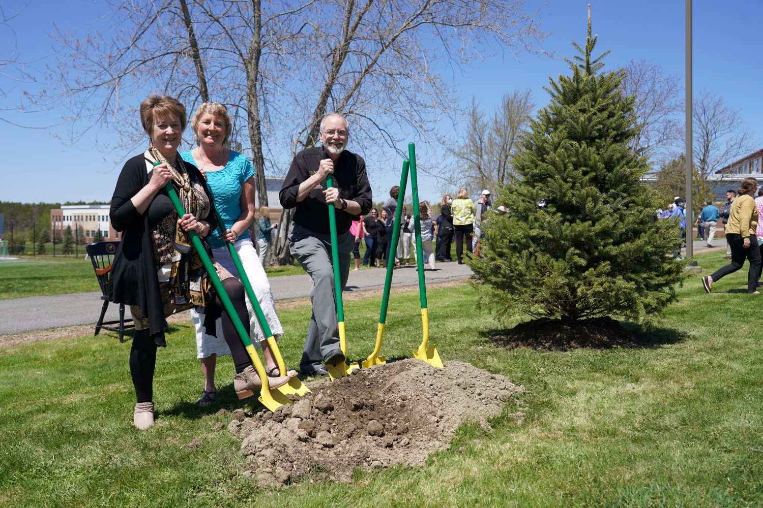 three people standing next to a tree