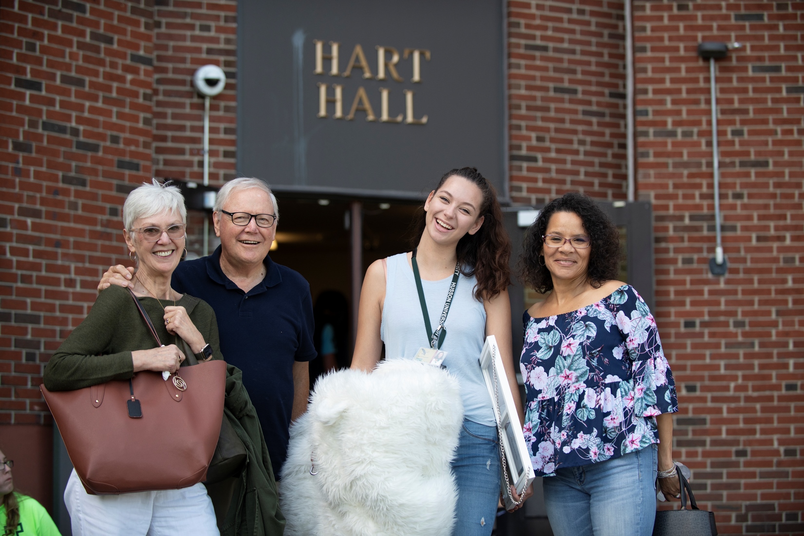 family posing with student in front of building