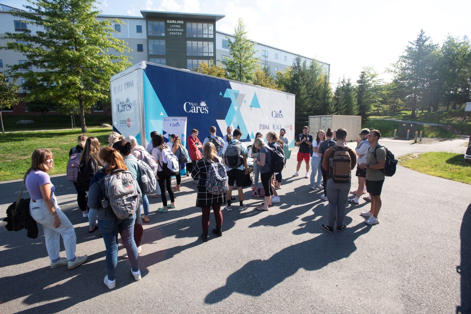 a group of people gathers around a RALI trailer