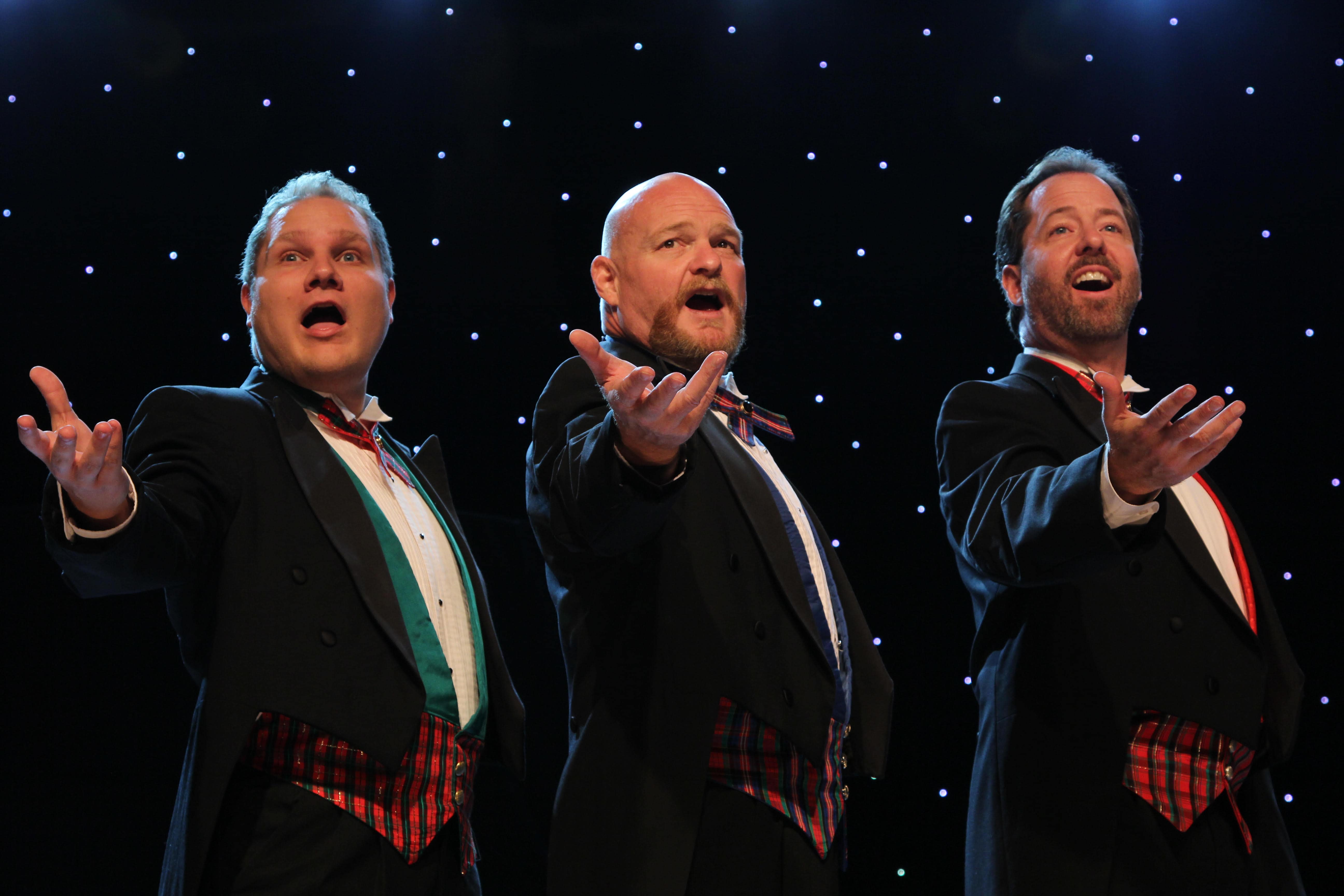 three men standing next to each other while singing