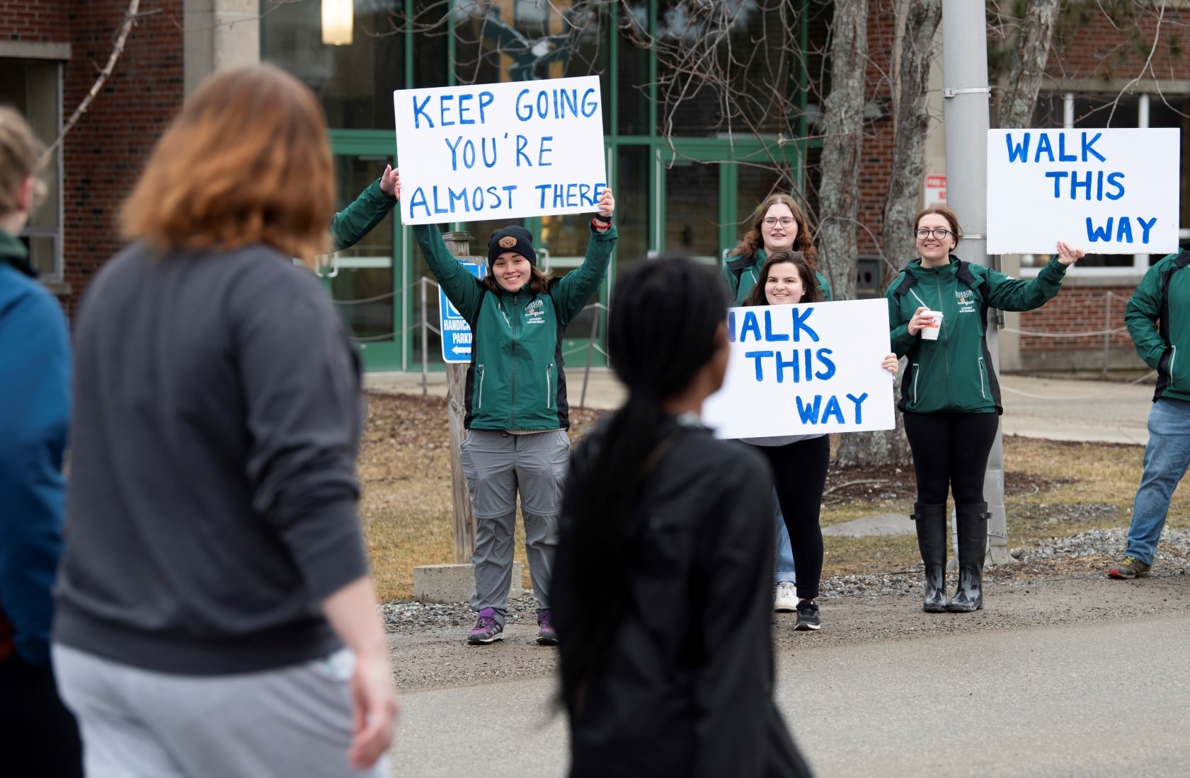 Students holding up motivational signs during the Walk for Warmth.