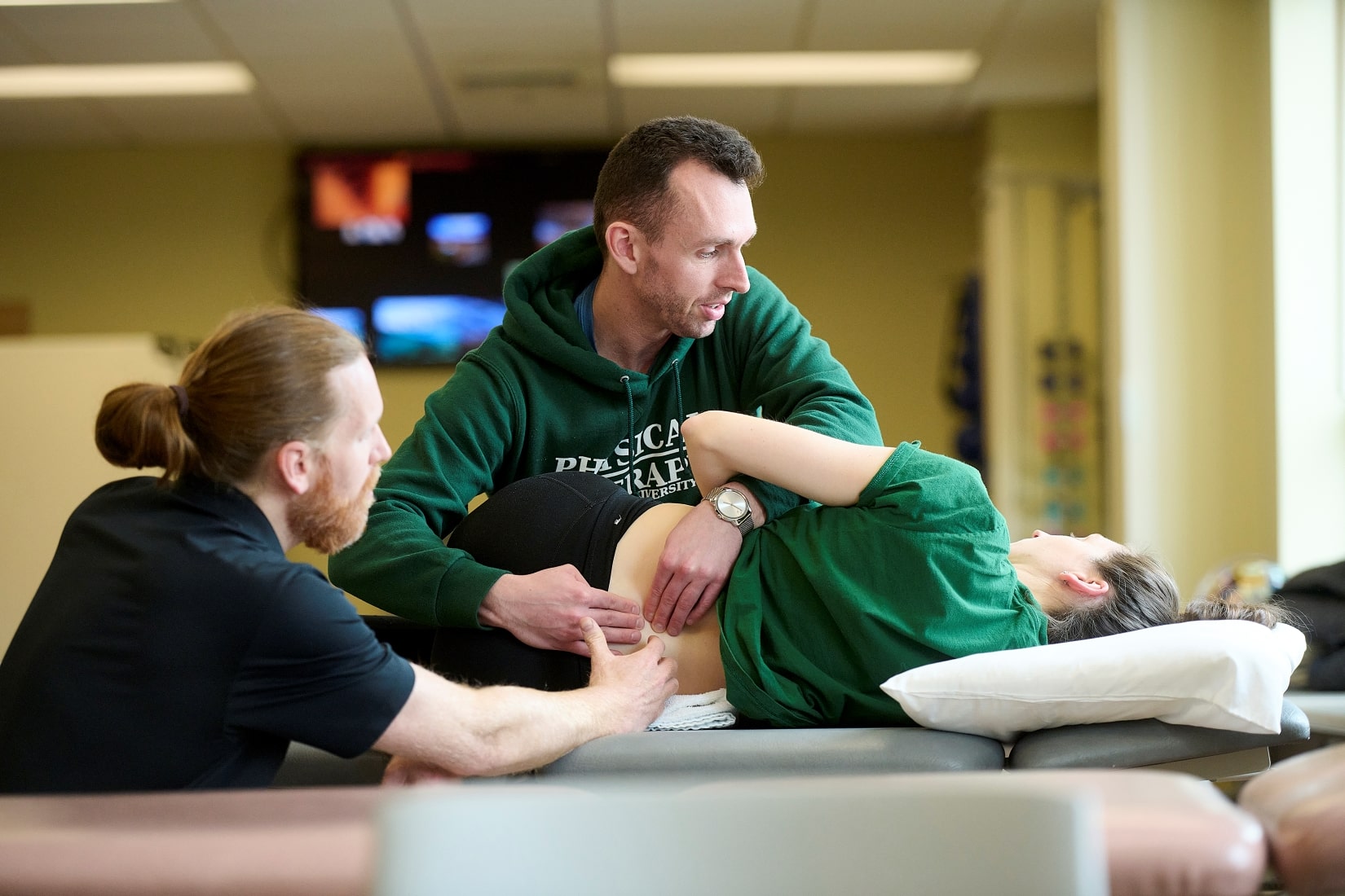 Two physical therapists performing a physical therapy session.