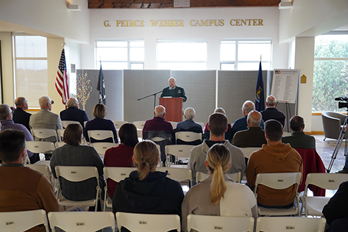 President Robert Clark of Husson University is shown addressing a crowd from a podium at the G. Peirce Webber Campus Center during a Veterans Day presentation in 2023.
