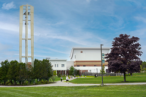 Husson's campus is shown including buildings, greenery and a bell tower.