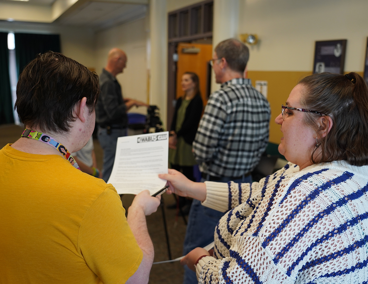 Two people hold a job application (one from each side) while talking. They are shown from the back.