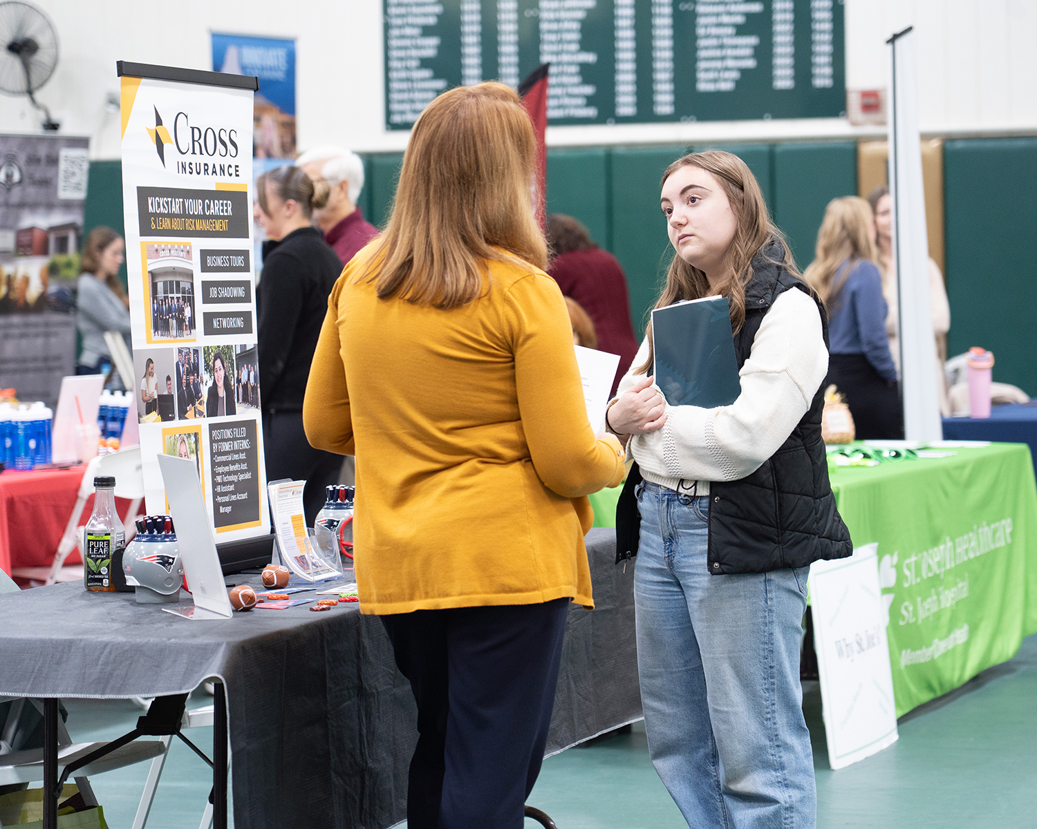 Two women speak at a career fair.