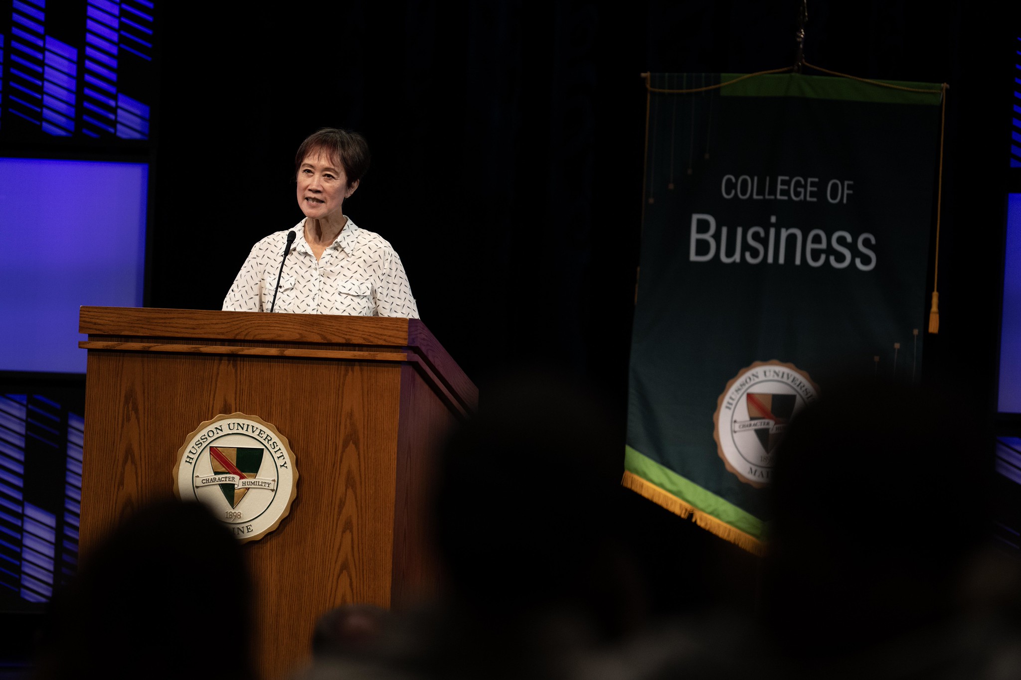 A woman stands at a podium speaking.